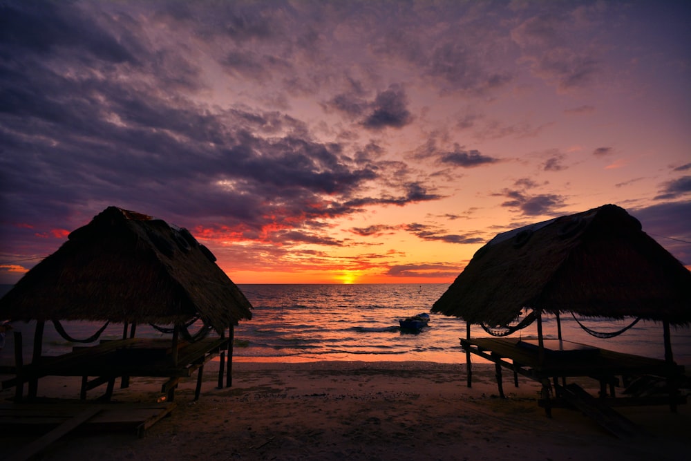 a couple of thatched umbrellas sitting on top of a beach