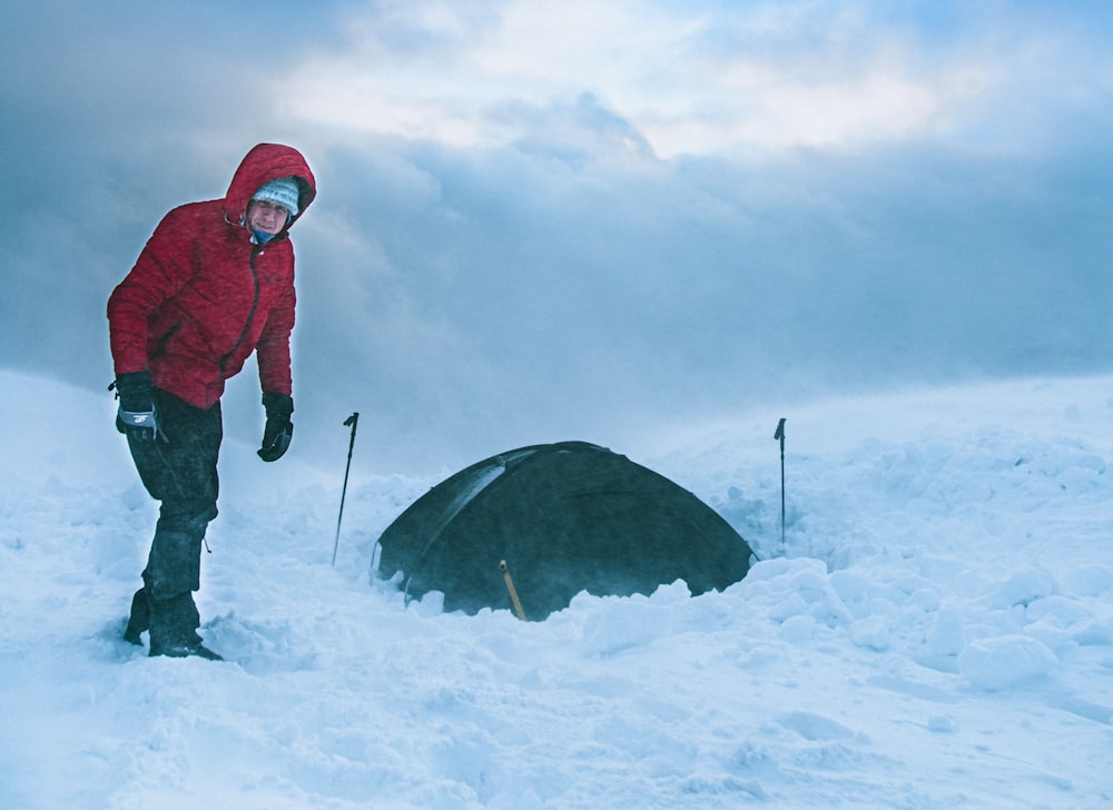 a man standing in the snow next to a tent