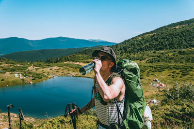 a man with a backpack drinking from a water bottle