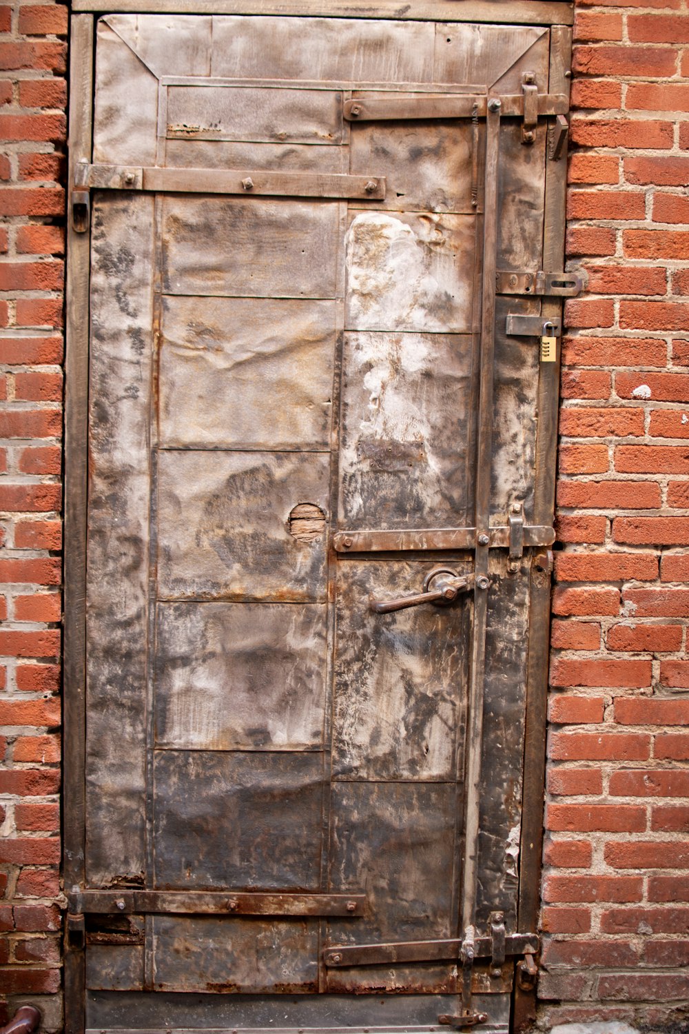 a rusted metal door on a brick wall