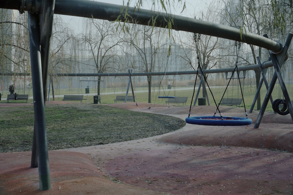 a swing set in a park with trees in the background