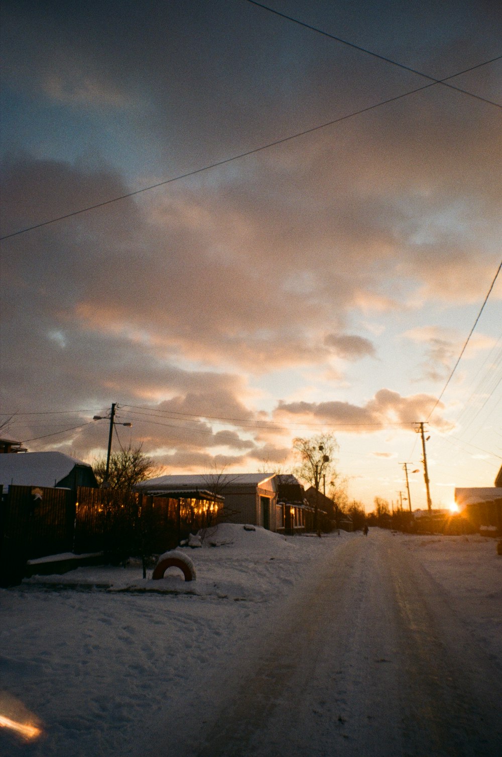 the sun is setting on a snowy street