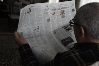 a man reading a newspaper while wearing glasses