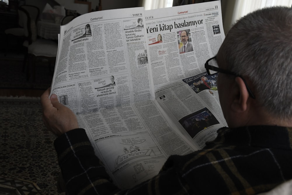 a man reading a newspaper while wearing glasses