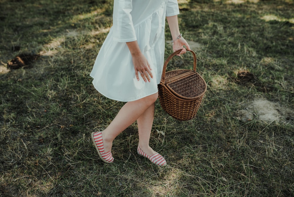 a woman in a white dress carrying a basket