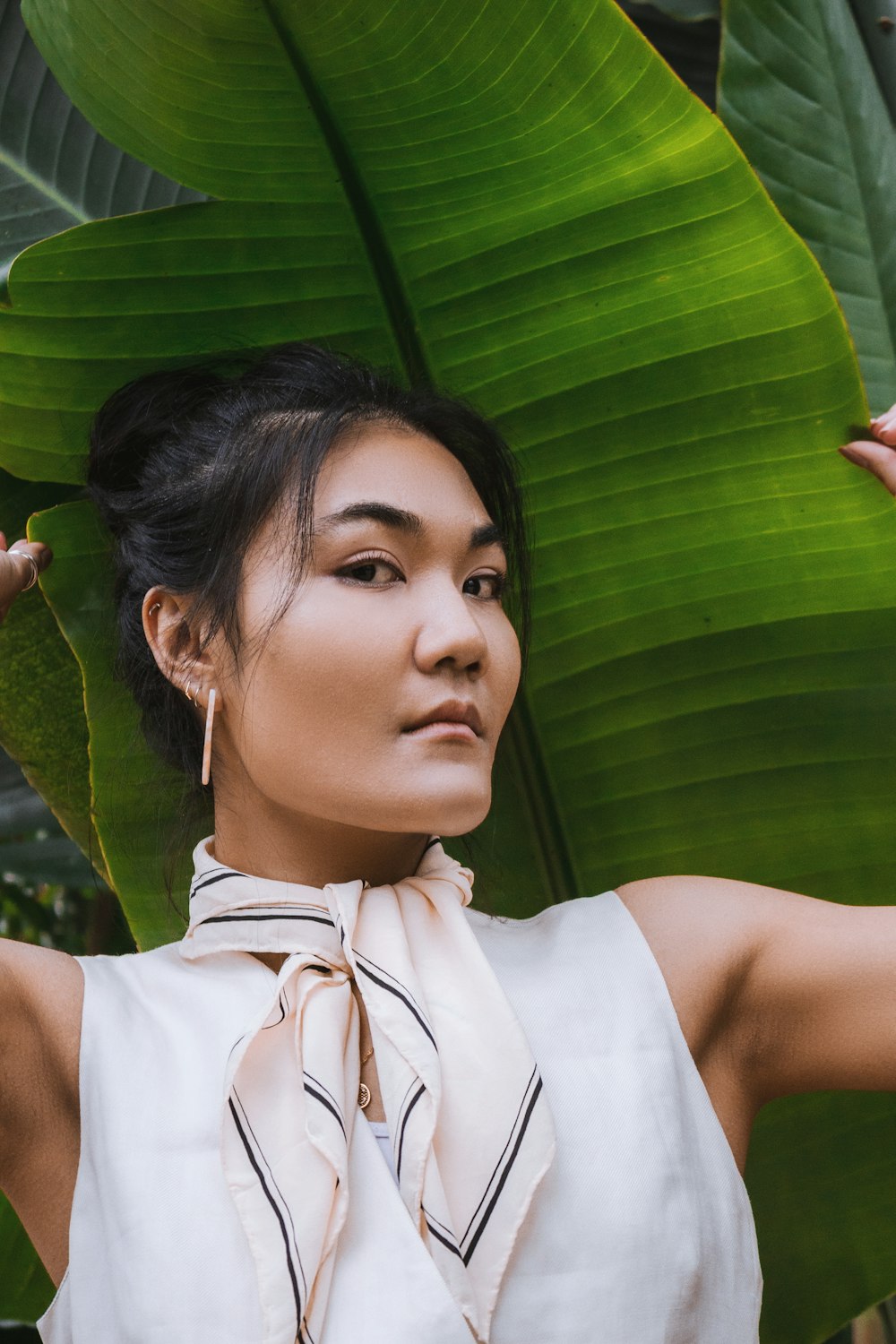 a woman standing in front of a large green leaf