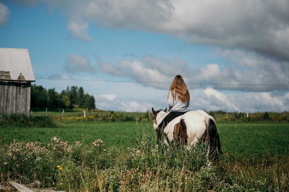 Eine Frau reitet auf dem Rücken eines weiß-braunen Pferdes