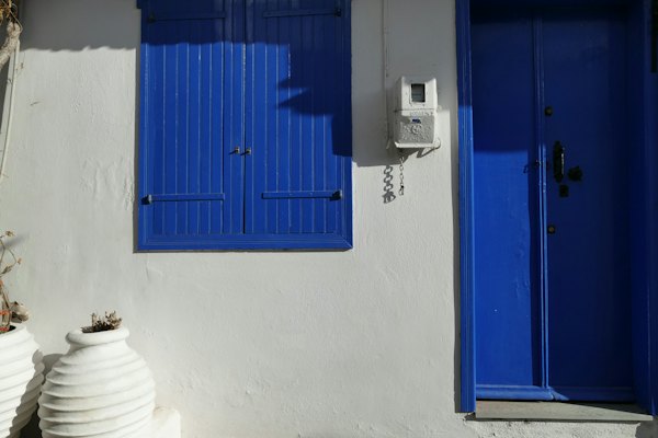 A white building with blue shutters and a phone — Skopelos, Greece