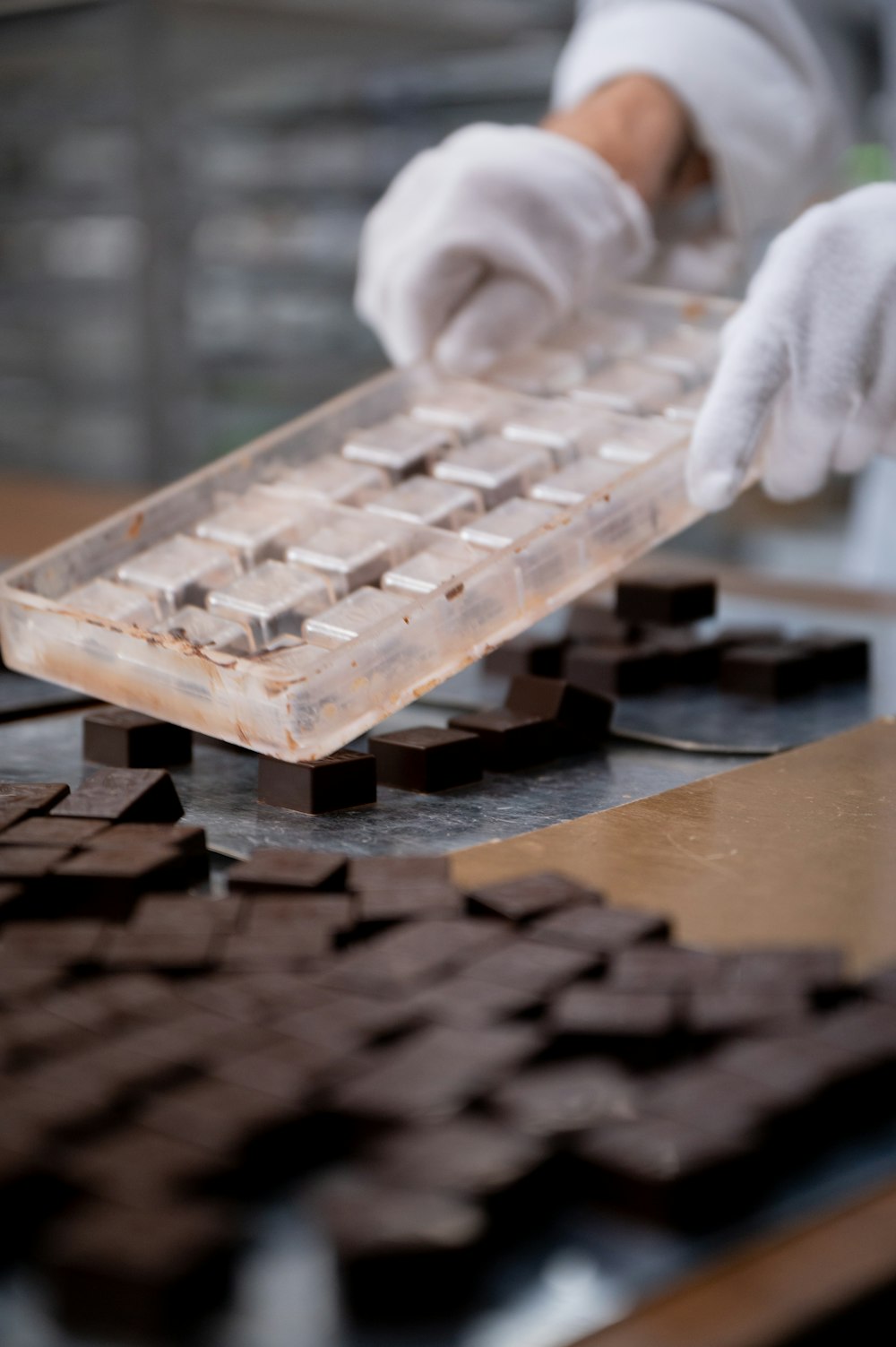 a person in white gloves and gloves working on a piece of chocolate