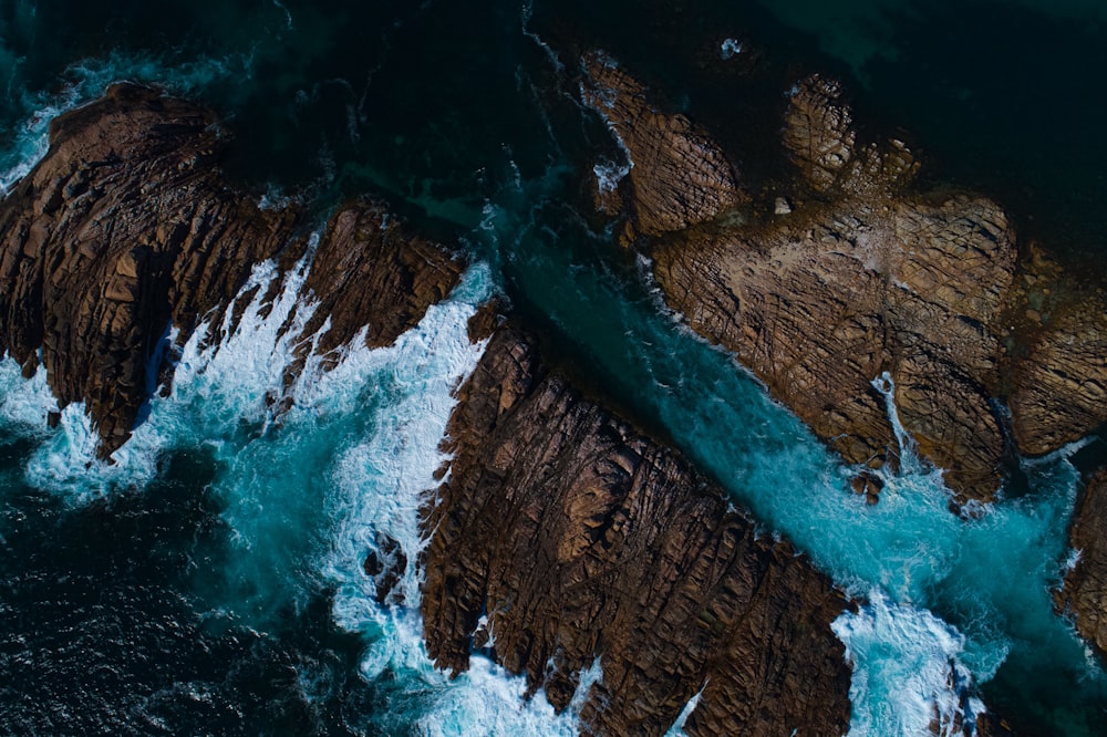 an aerial view of the ocean and rocks