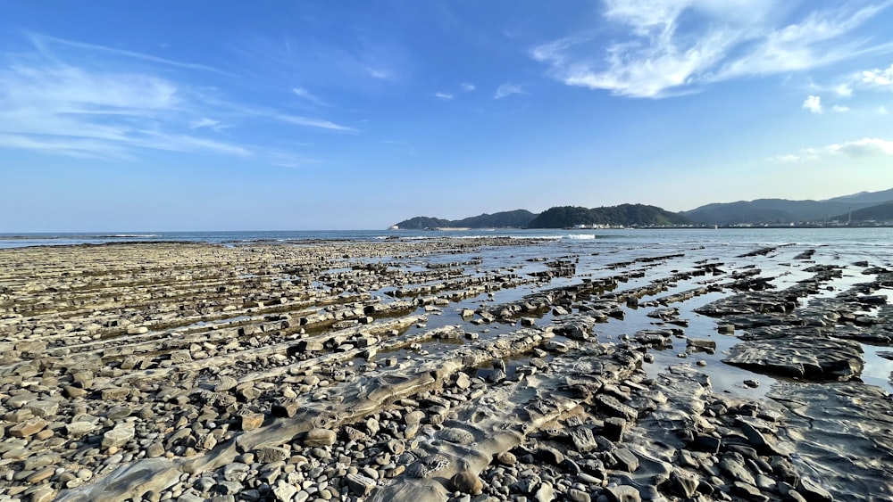 a beach with rocks and water under a blue sky