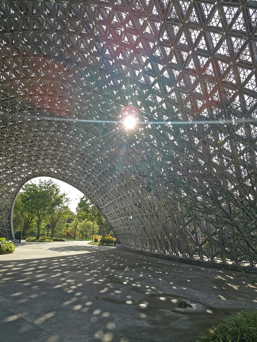 the sun shines through a metal structure in a park