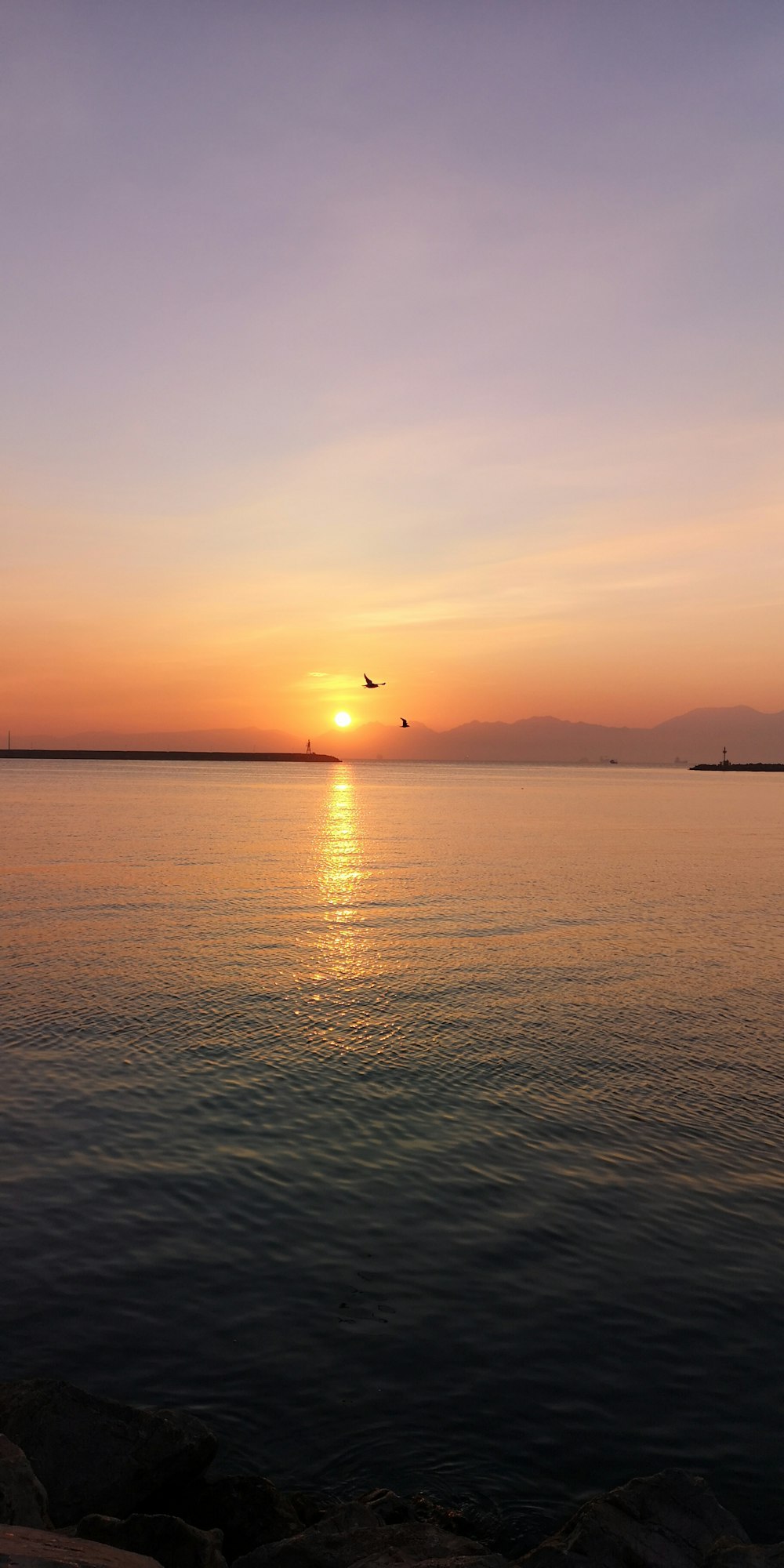 a large body of water with a sunset in the background