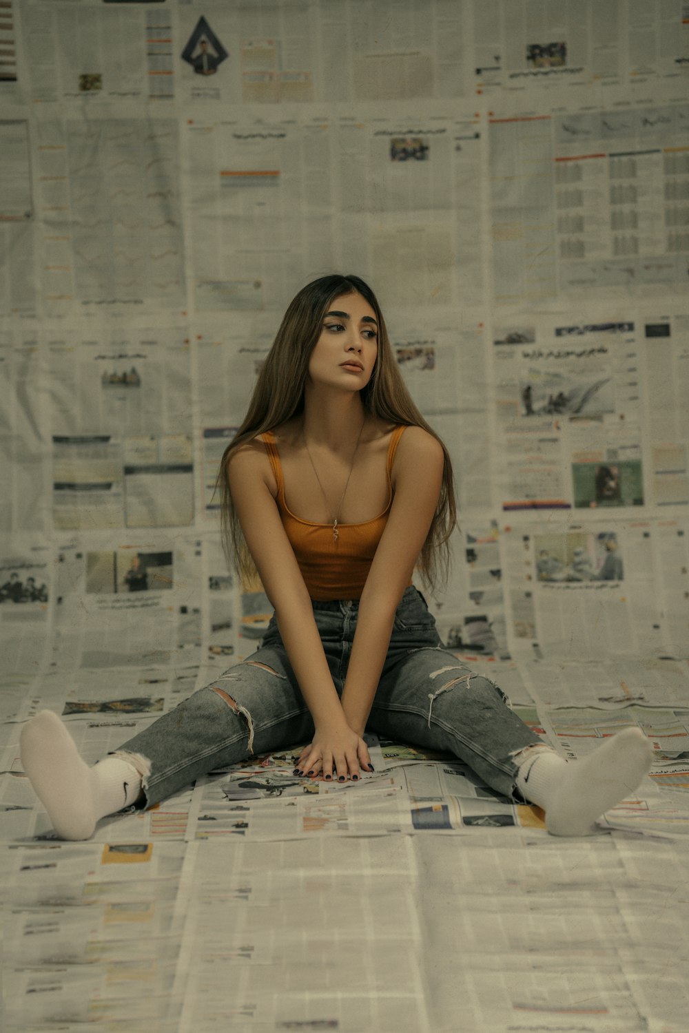 a woman sitting on top of a newspaper covered floor