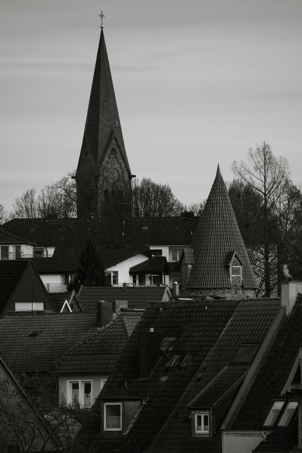 a black and white photo of rooftops with a church steeple in the background