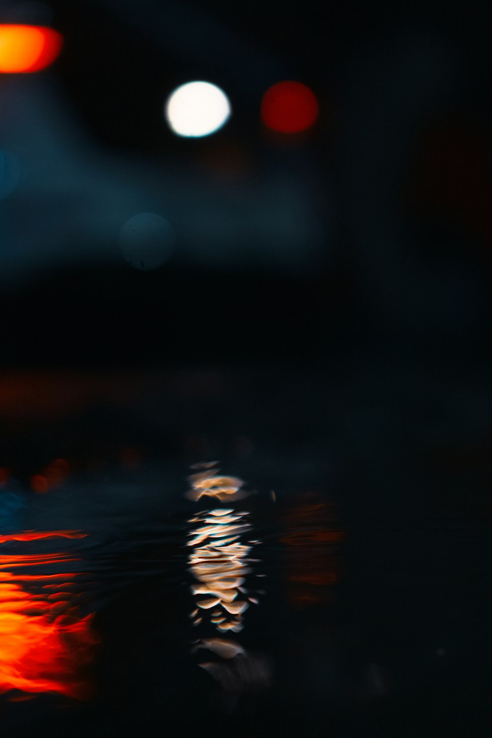 a blurry image of a street light reflecting off of the water