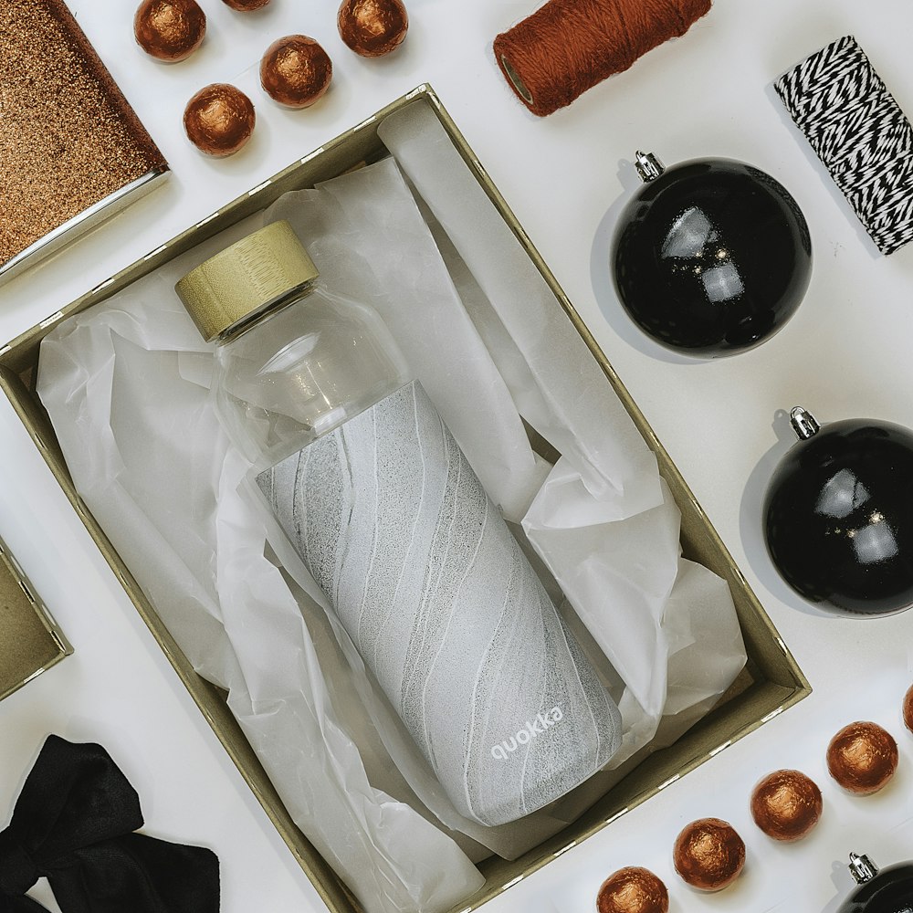 a bottle of water in a box surrounded by christmas ornaments