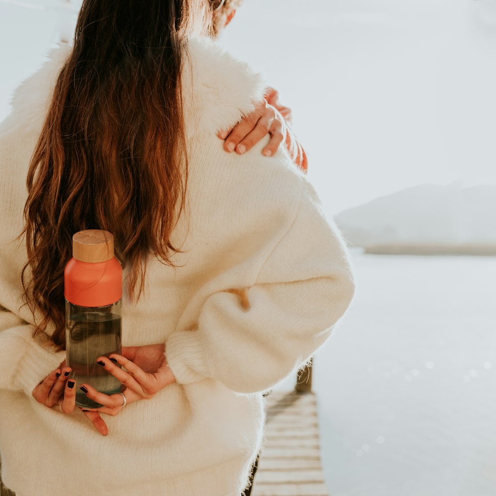 a woman in a white sweater holding a water bottle