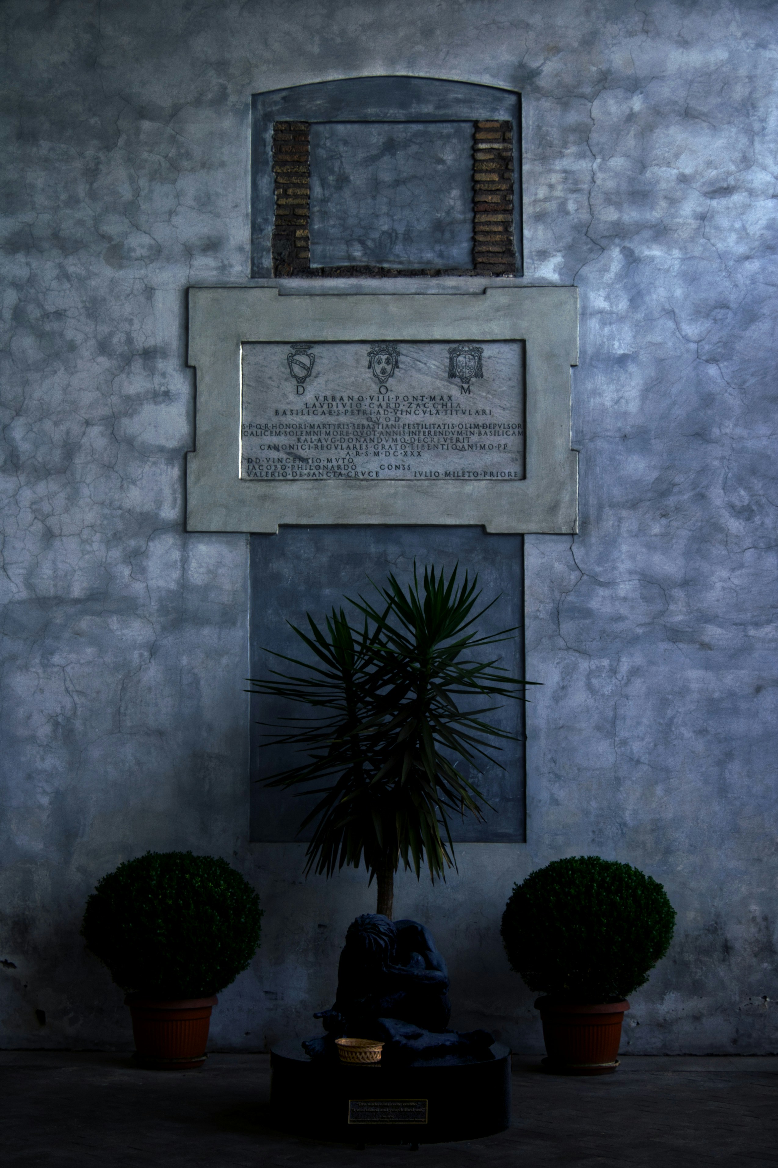 a wall with a plaque and two potted plants