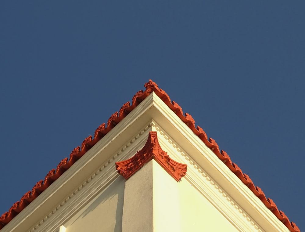 a white building with a red roof and a blue sky