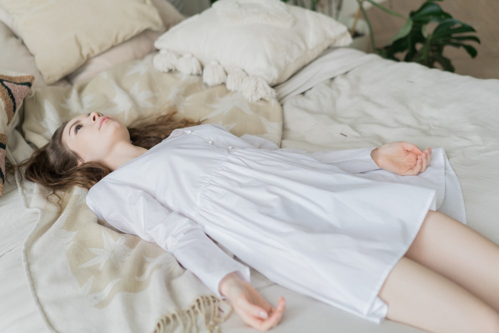 a woman laying on top of a bed next to a stuffed animal