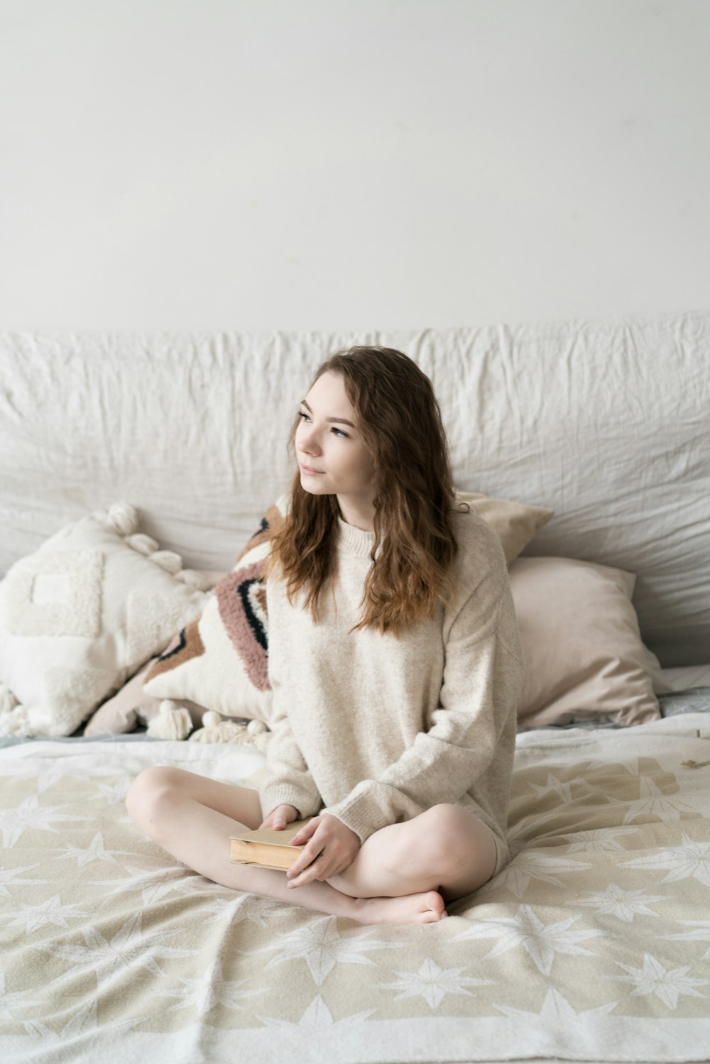 a woman sitting on top of a bed next to pillows