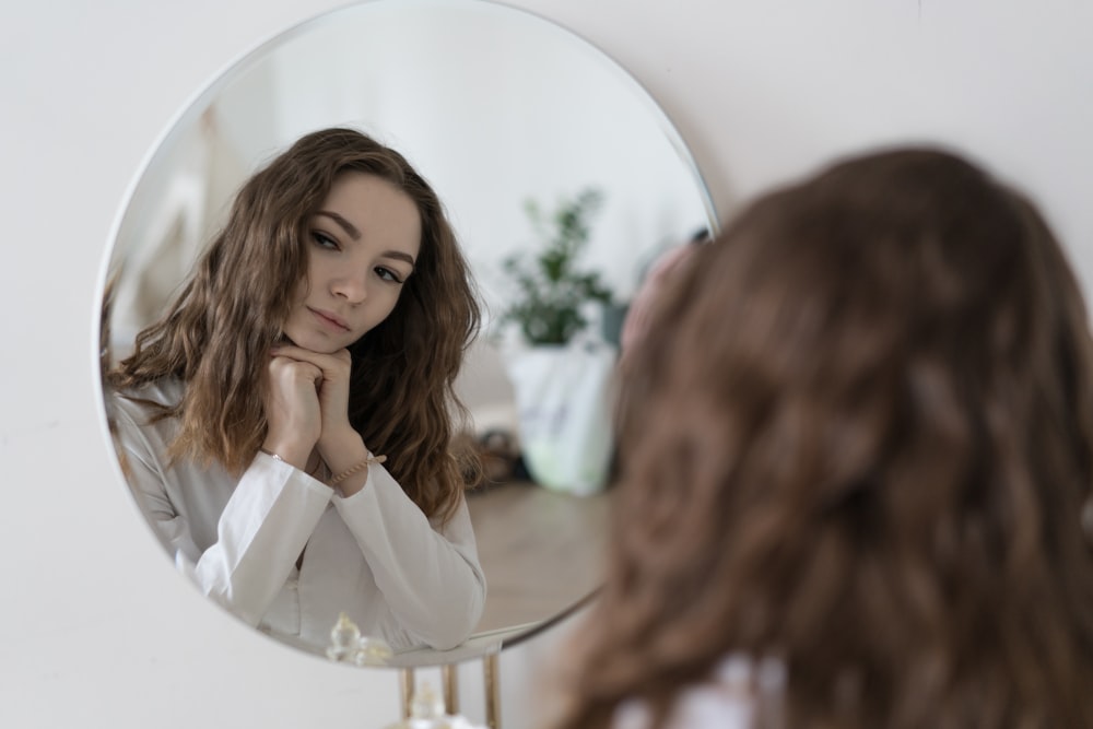 a woman looking at her reflection in a mirror