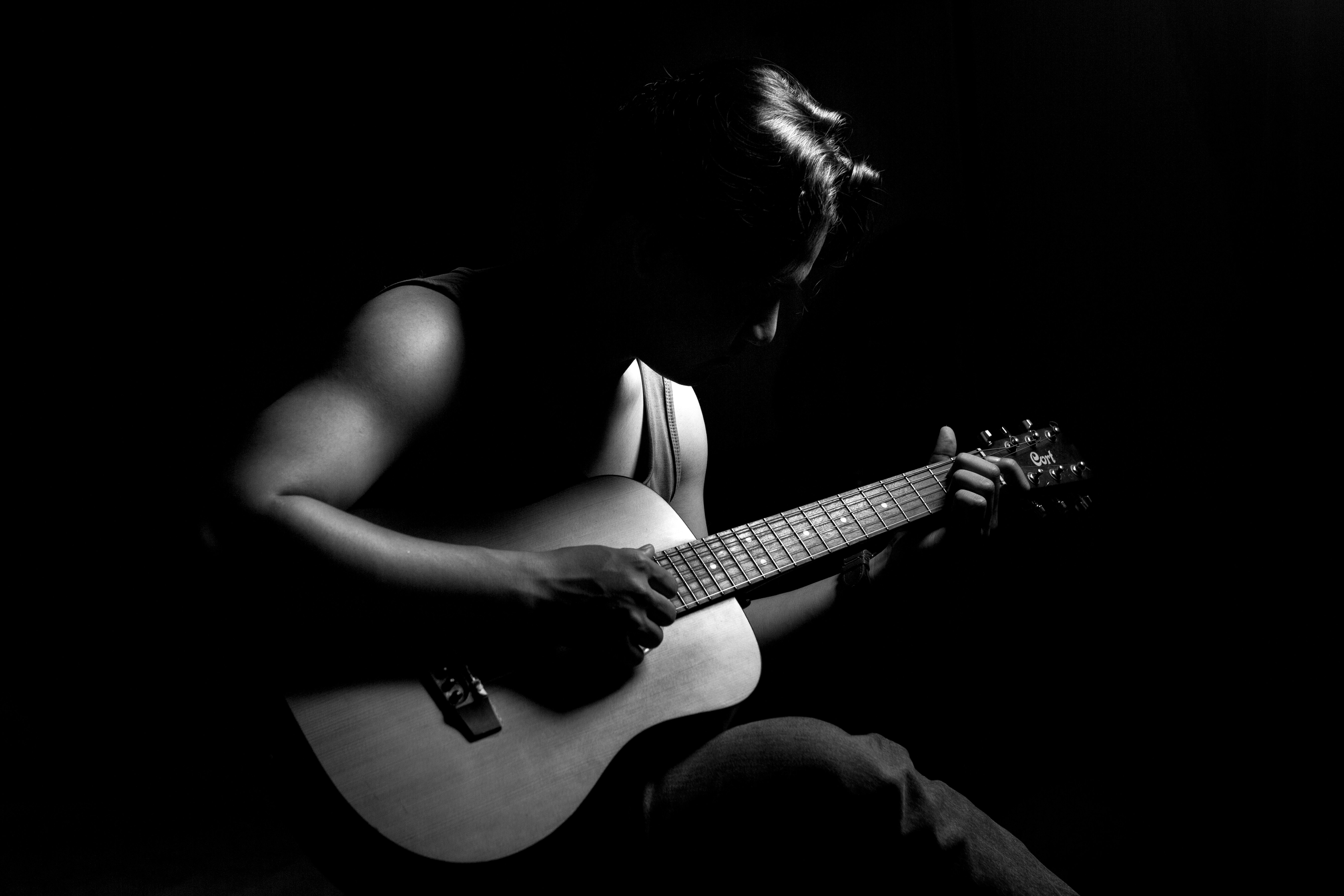 a person sitting in the dark playing a guitar