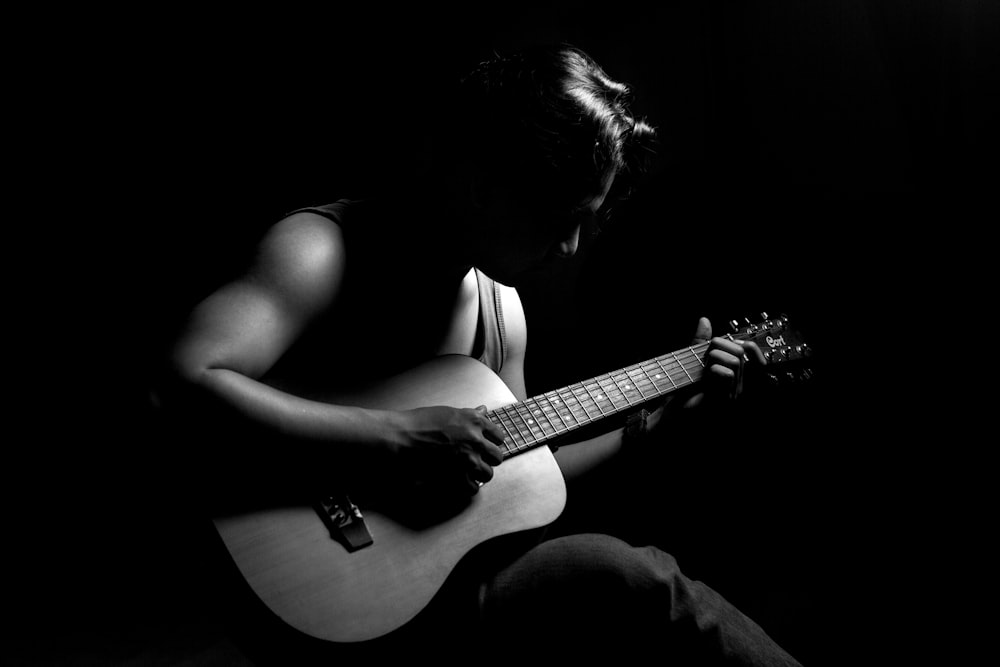 a person sitting in the dark playing a guitar