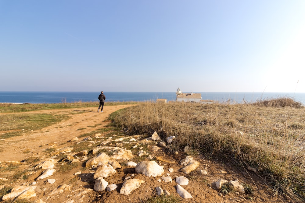 a man standing on a dirt road next to the ocean