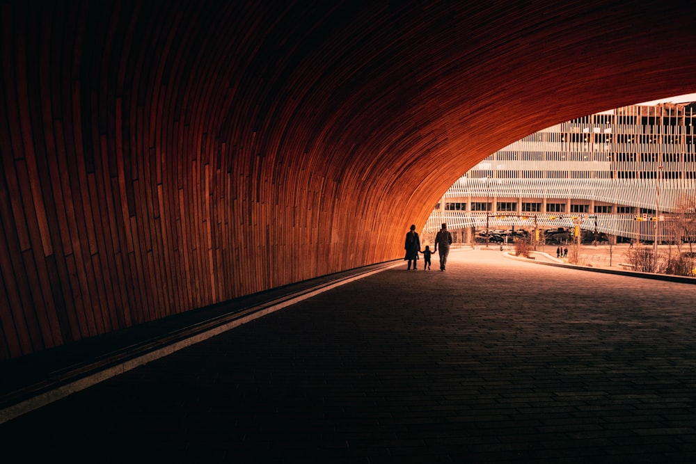 two people walking under a tunnel in a city