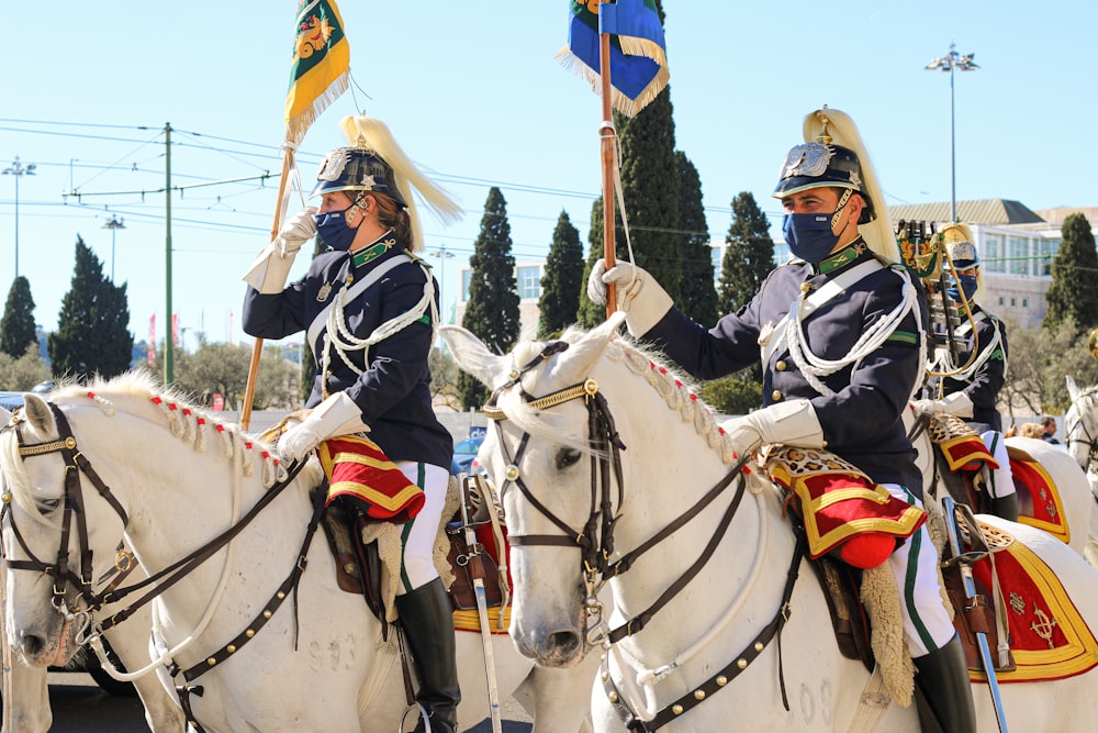 a couple of men riding on the back of white horses