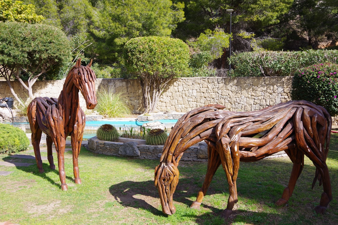 a couple of wooden horses standing on top of a lush green field