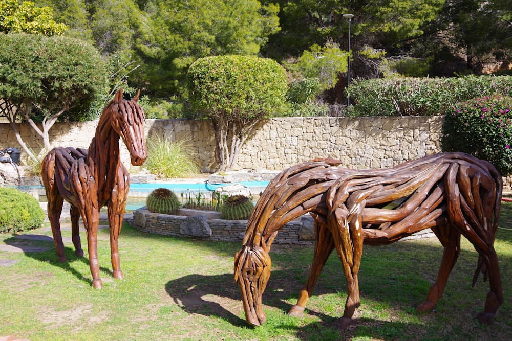 a couple of wooden horses standing on top of a lush green field