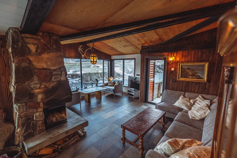 Interior cálido de un chalet de madera con chimenea de piedra encendida