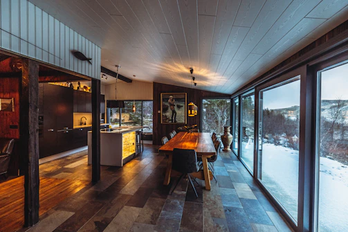 a dining room with a wooden table surrounded by windows