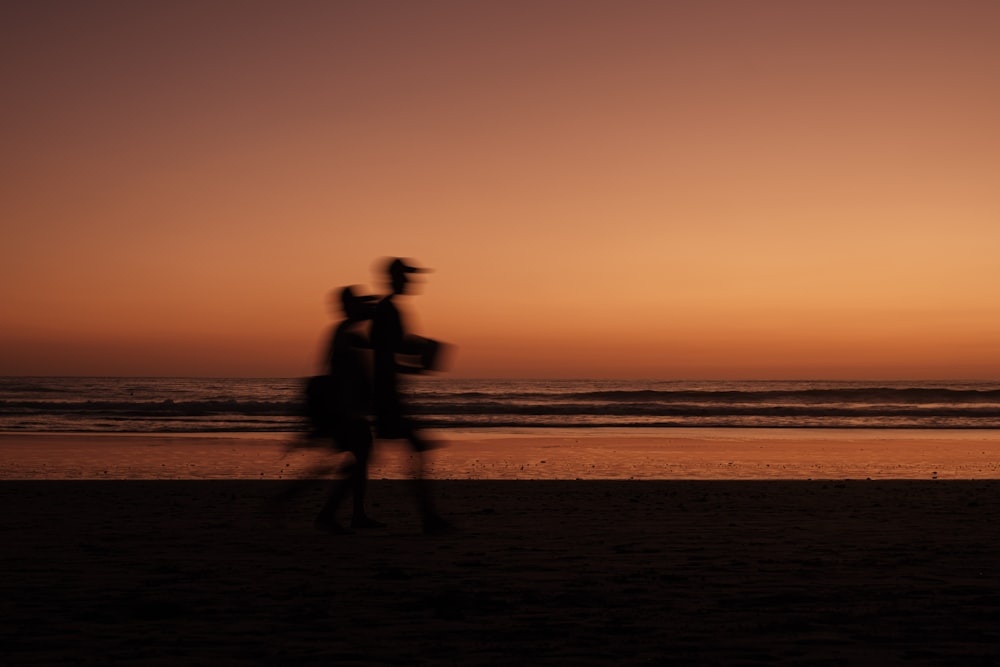 a man and a woman walking on a beach at sunset
