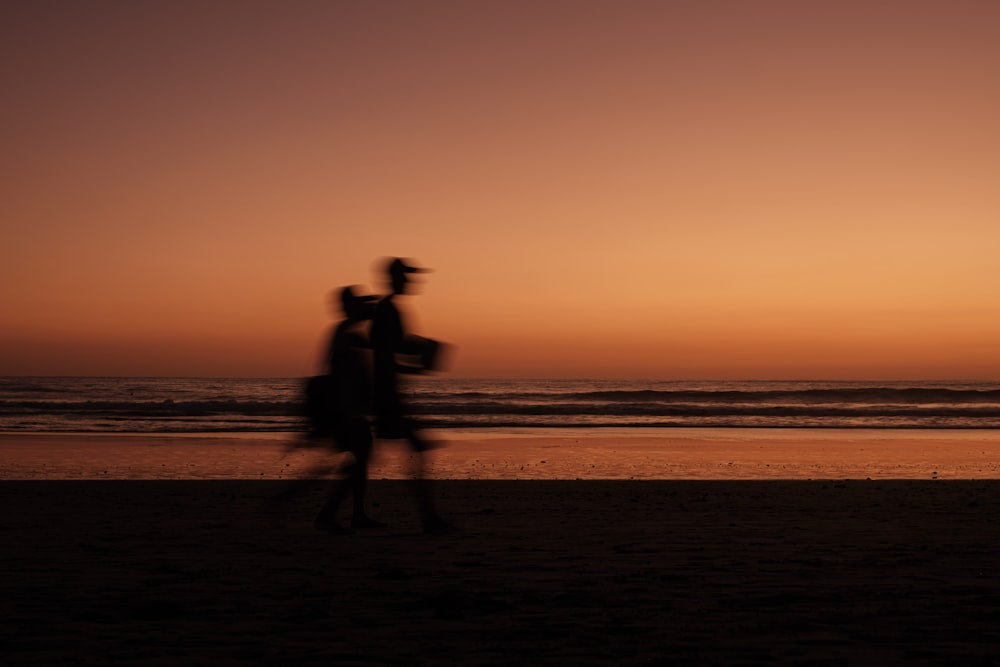 Un hombre y una mujer caminando por una playa al atardecer