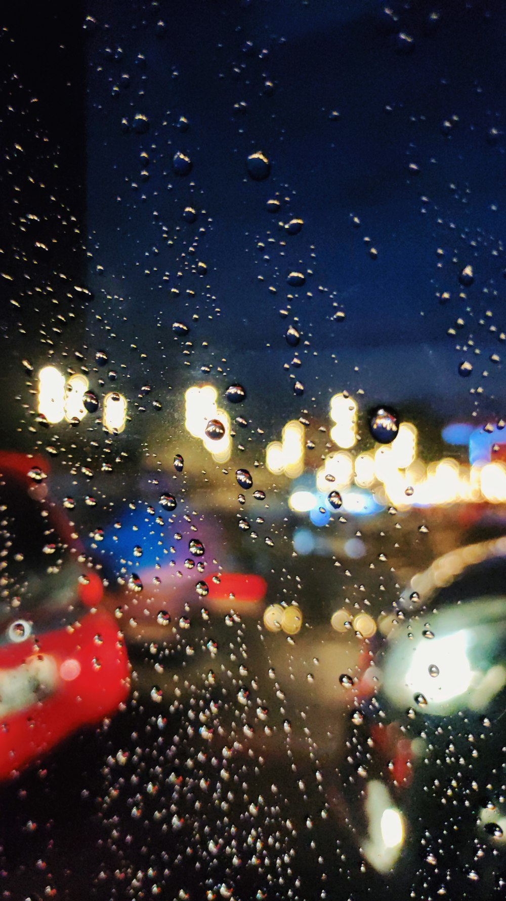 rain drops on a window as cars drive down the street