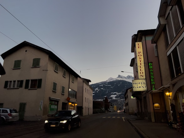 A sleek taxi driving through a snowy Austrian mountain village at dusk.