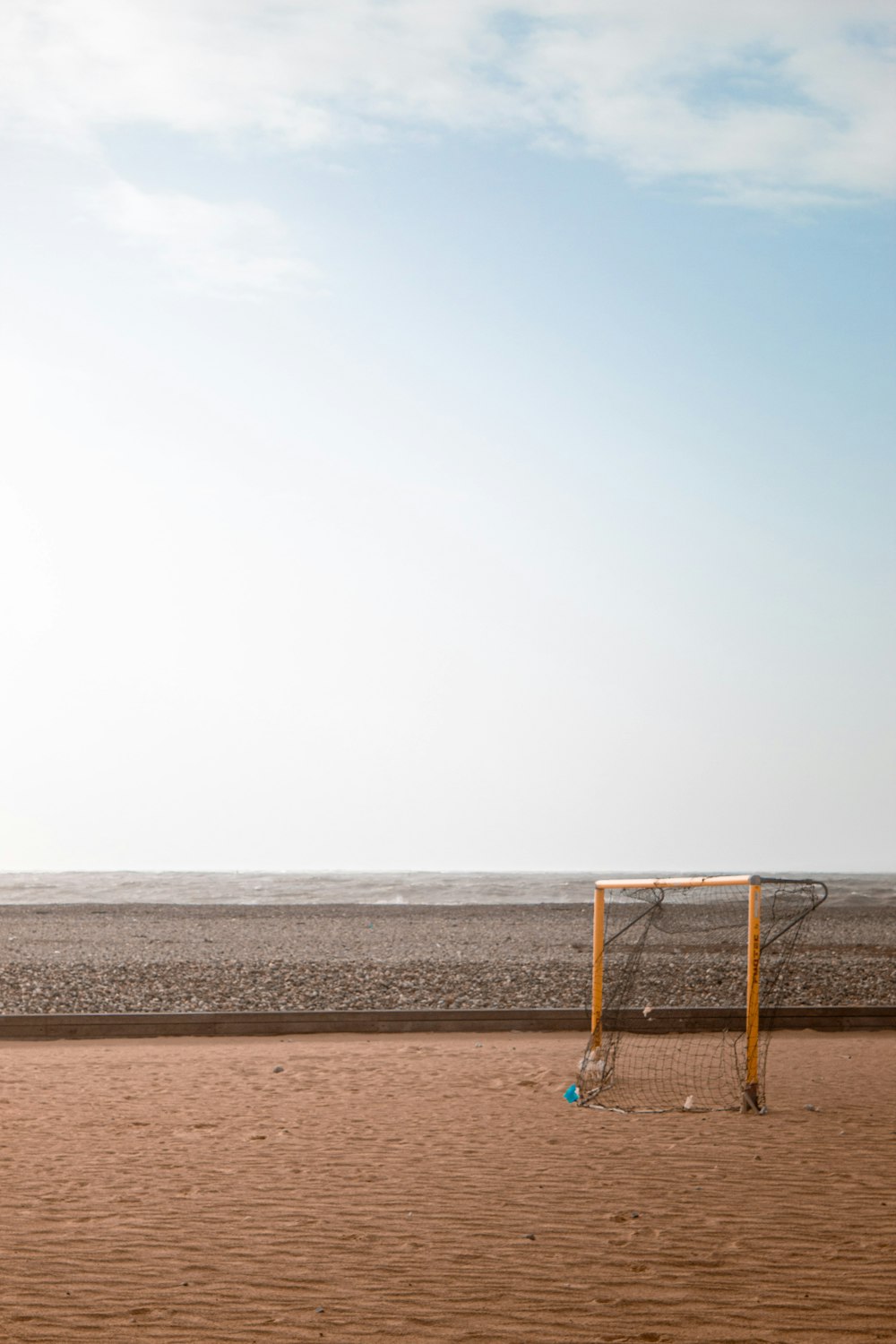 a soccer goal on a beach with a sky background