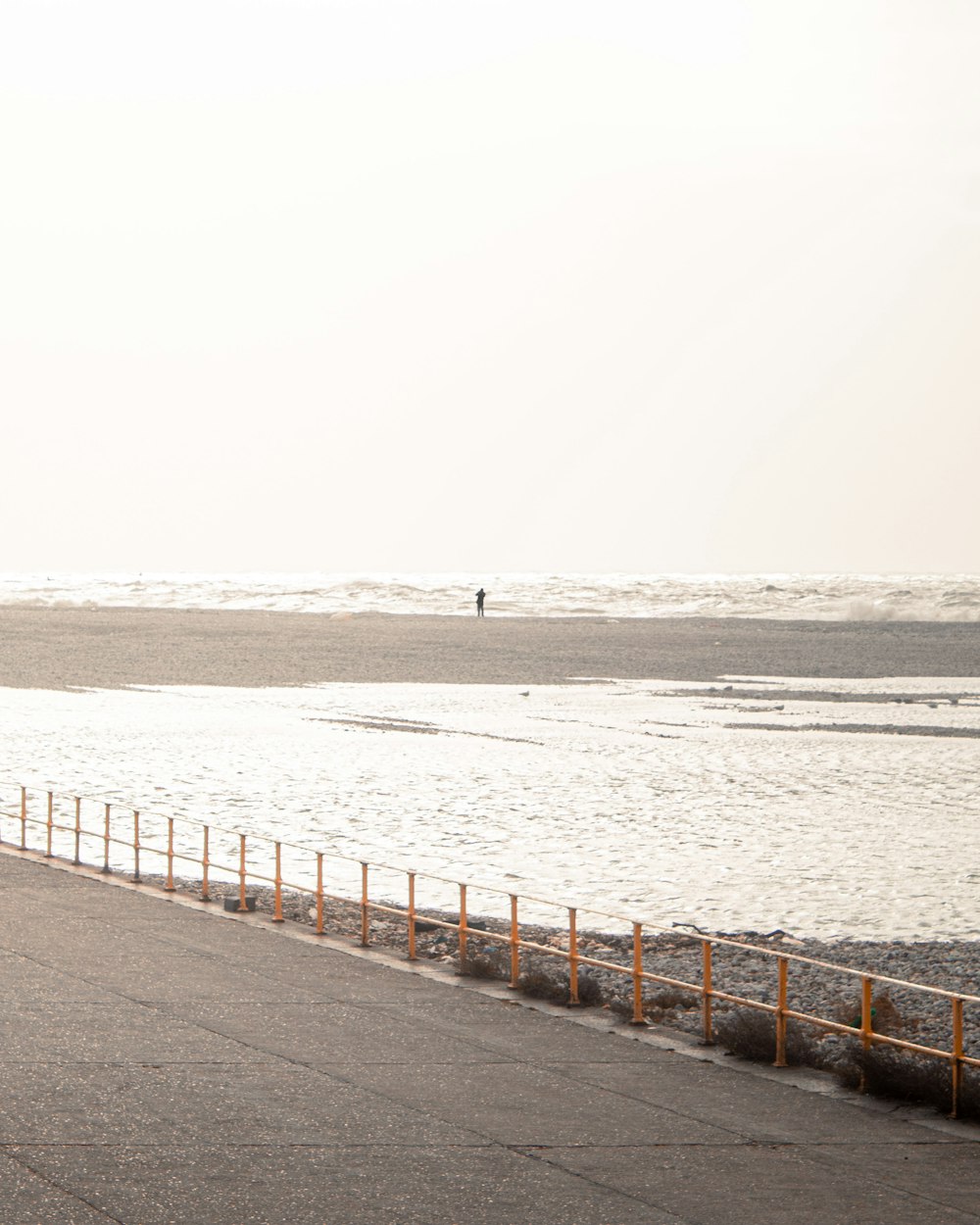 a man riding a surfboard down a road next to the ocean