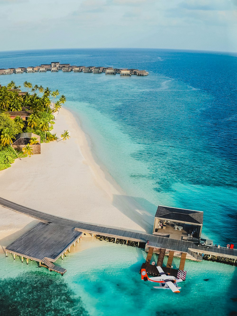 an aerial view of a beach with a dock and a boat