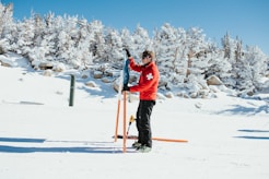 a person in a red jacket holding skis and poles in the snow