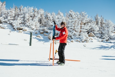 a person in a red jacket holding skis and poles in the snow