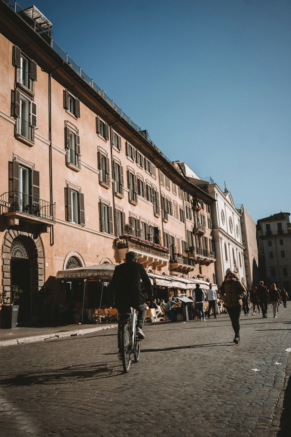 a man riding a bike down a street next to a tall building