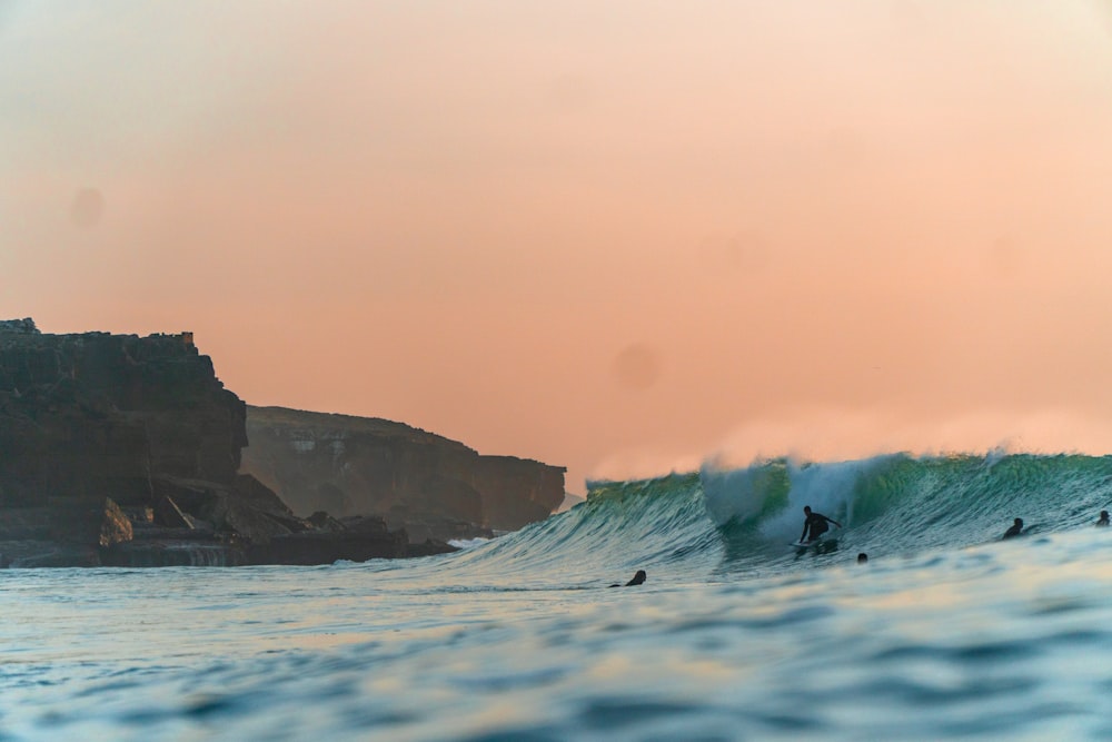 a group of people riding waves on top of surfboards