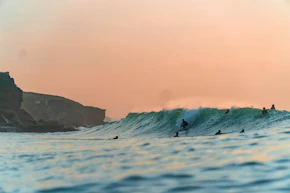 a group of people riding surfboards on top of a wave