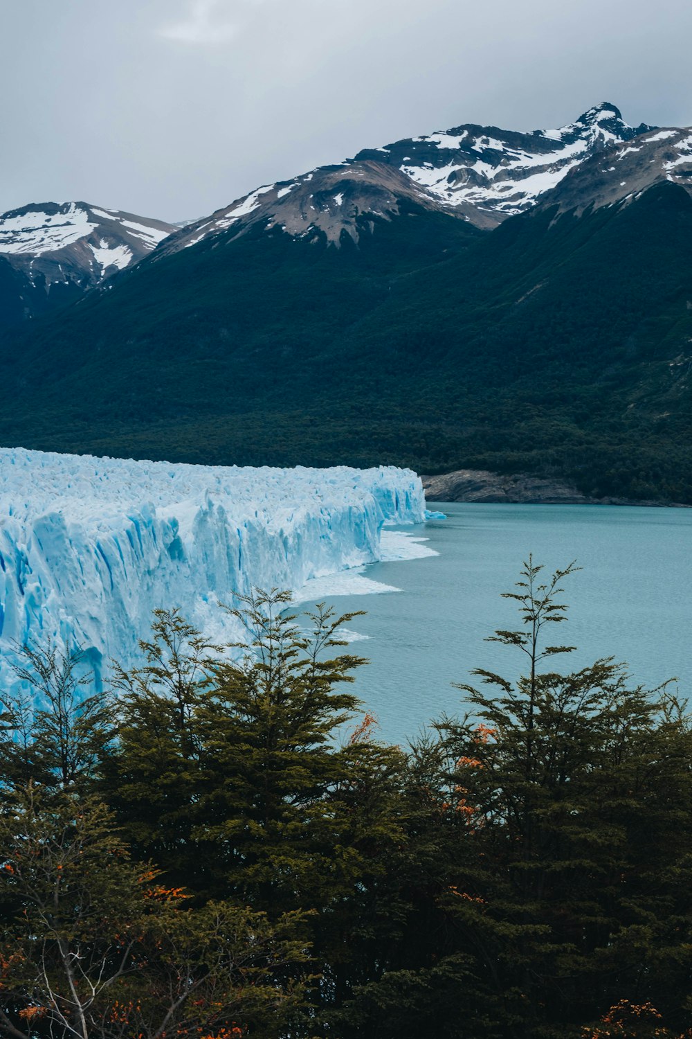 a large blue glacier with mountains in the background