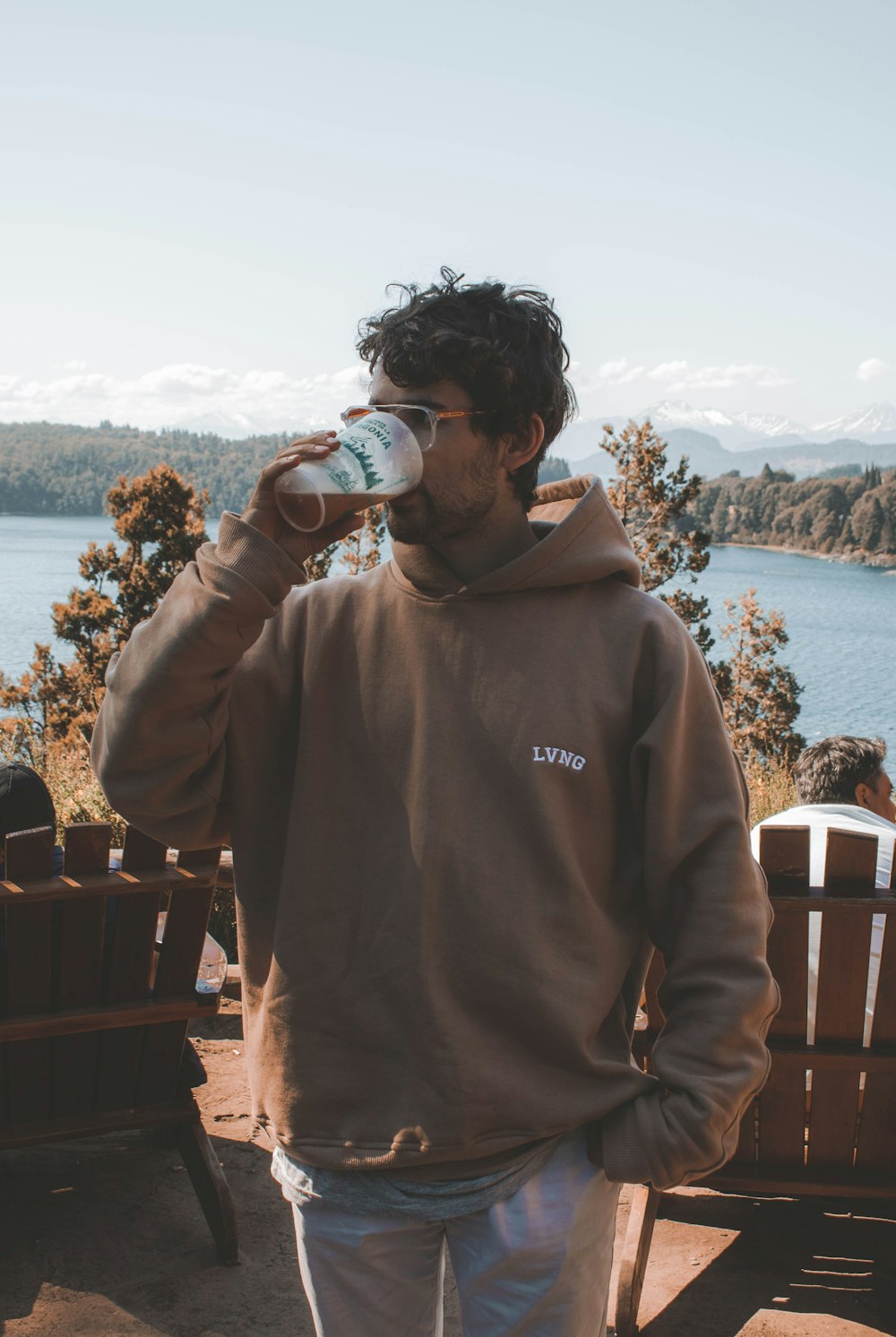 a man standing on a deck drinking from a cup